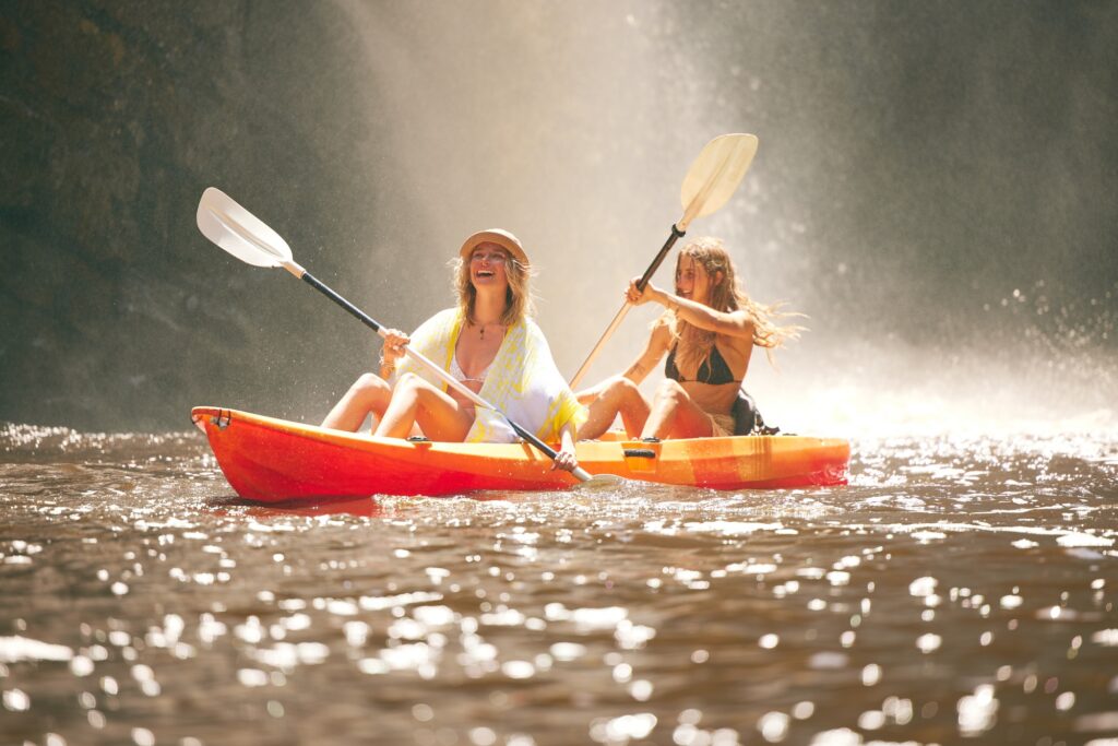 Happy friends kayak on the lake or river together during summer vacation. Free, freedom and rowing